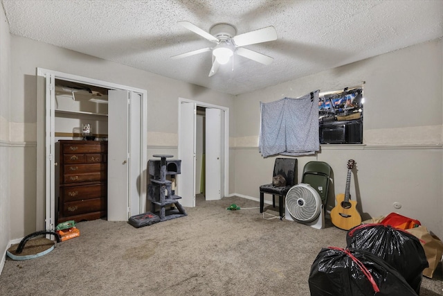 interior space featuring a textured ceiling, carpet flooring, and a ceiling fan