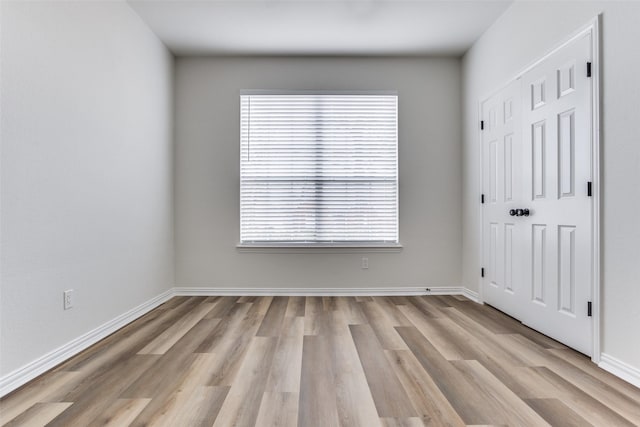 spare room with plenty of natural light, baseboards, and light wood-style flooring