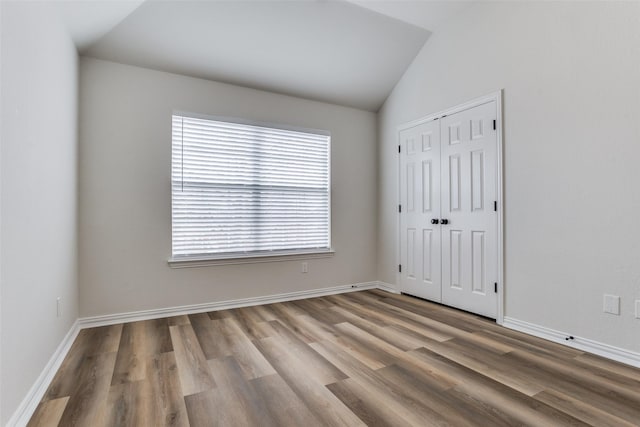 empty room with lofted ceiling, baseboards, and wood finished floors