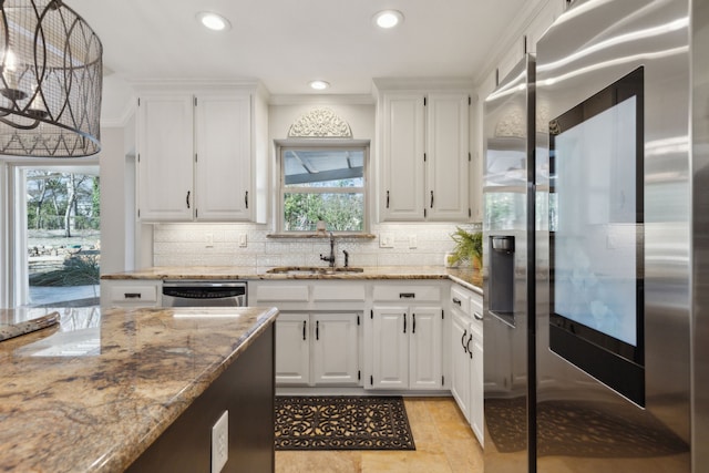 kitchen featuring white cabinets, appliances with stainless steel finishes, light stone countertops, and a sink