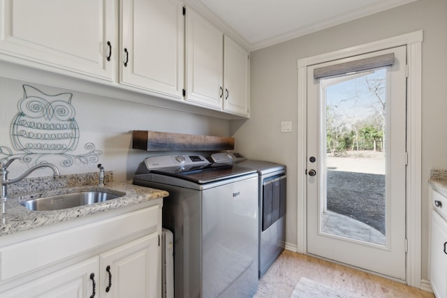 laundry area featuring washing machine and clothes dryer, ornamental molding, cabinet space, and a sink