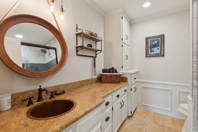 bathroom featuring toilet, ornamental molding, wainscoting, a decorative wall, and tiled shower