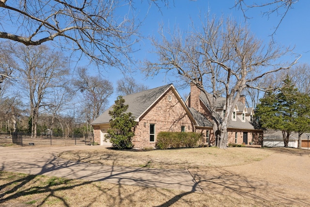 view of front facade with driveway, fence, an attached garage, brick siding, and a chimney