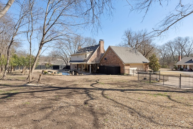 view of side of property featuring a patio area, a chimney, an attached garage, and fence