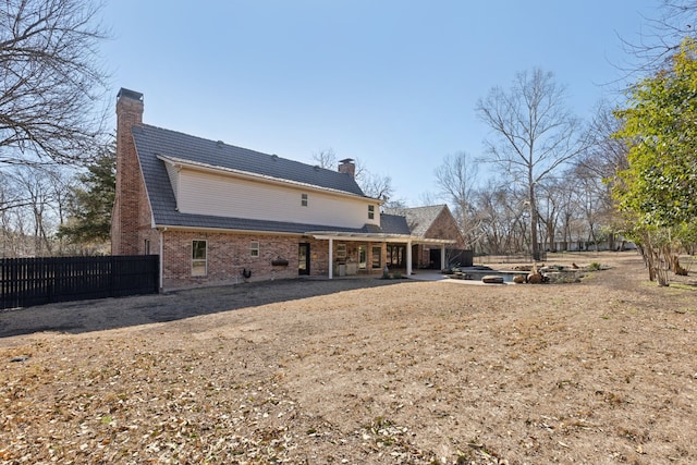 back of property with a patio area, brick siding, a chimney, and fence