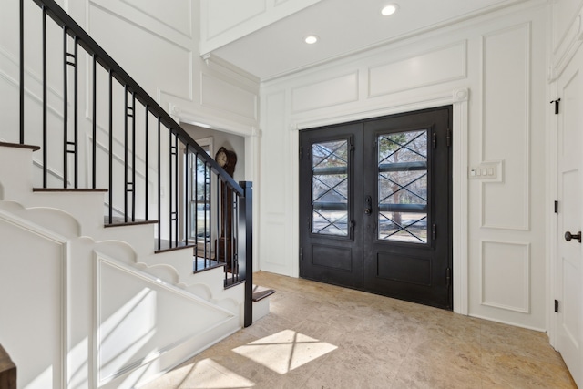 foyer with stairway, recessed lighting, ornamental molding, french doors, and a decorative wall