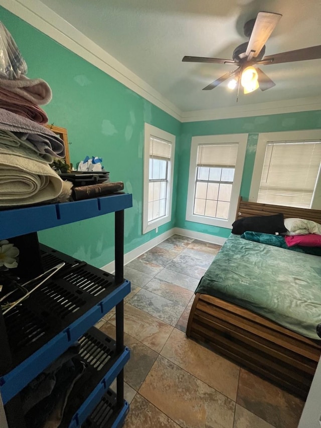 bedroom with stone finish floor, baseboards, ornamental molding, and a ceiling fan