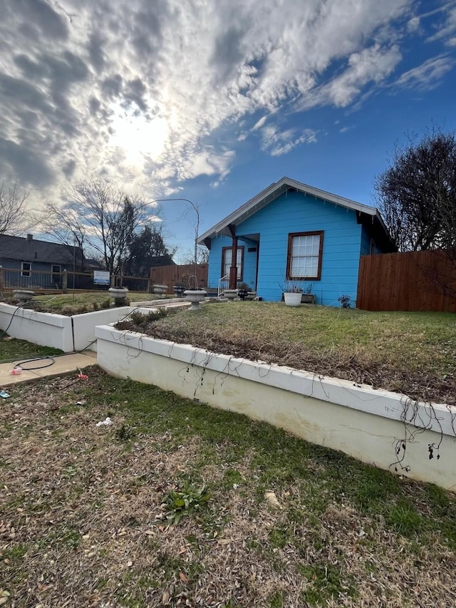 view of side of home with fence and a lawn