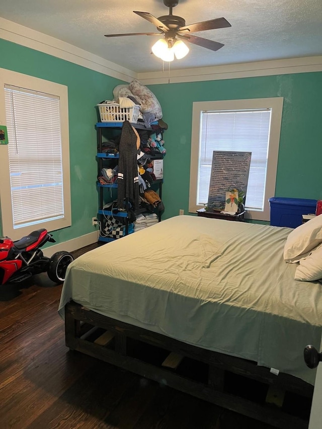 bedroom featuring a ceiling fan, a textured ceiling, ornamental molding, and wood finished floors