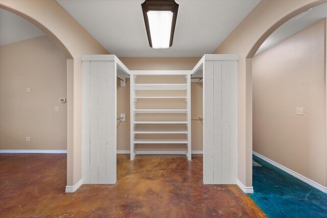 empty room with baseboards, ceiling fan, lofted ceiling, and finished concrete floors