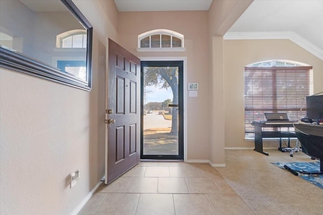 entryway with light colored carpet, plenty of natural light, baseboards, and light tile patterned floors