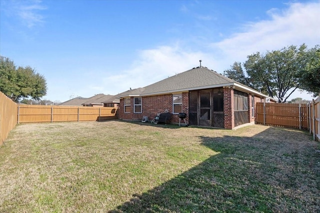 rear view of property featuring brick siding, a lawn, and a fenced backyard