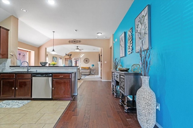 kitchen featuring arched walkways, decorative light fixtures, dark countertops, vaulted ceiling, and dishwasher