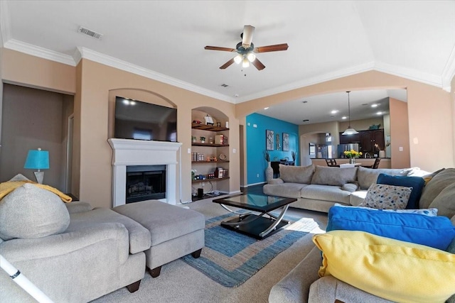 living area featuring a fireplace, carpet flooring, visible vents, built in features, and ornamental molding