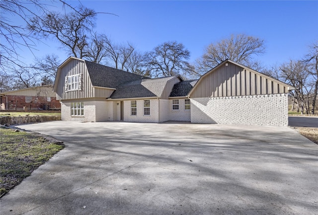 dutch colonial with driveway, brick siding, a shingled roof, and a gambrel roof