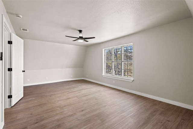 unfurnished room with a ceiling fan, visible vents, baseboards, and wood finished floors