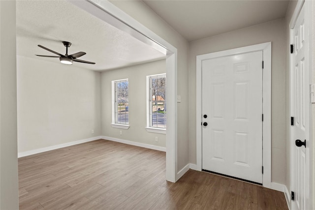 entryway featuring a ceiling fan, light wood-style flooring, baseboards, and a textured ceiling