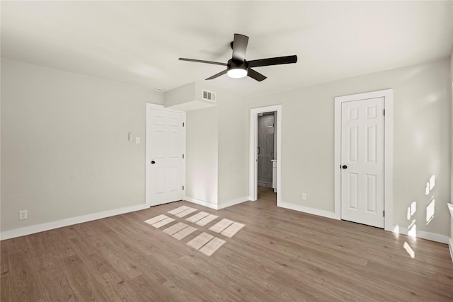 unfurnished bedroom featuring a ceiling fan, visible vents, baseboards, and wood finished floors