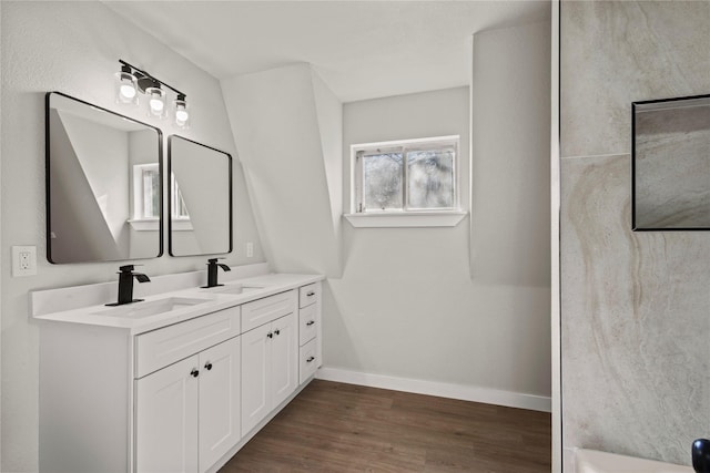 full bathroom featuring a sink, double vanity, baseboards, and wood finished floors