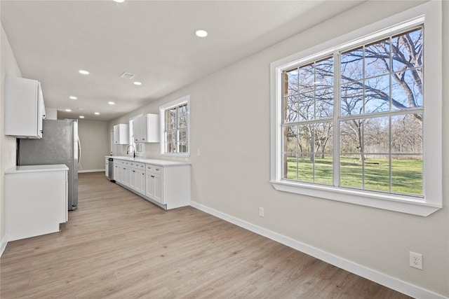 kitchen with baseboards, light countertops, light wood-style floors, and white cabinets