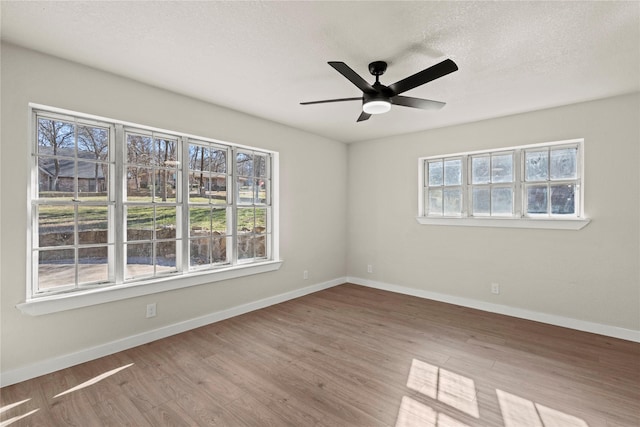 unfurnished room with a ceiling fan, a textured ceiling, baseboards, and wood finished floors