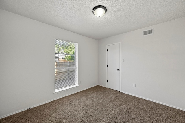 carpeted spare room with a textured ceiling, visible vents, and baseboards