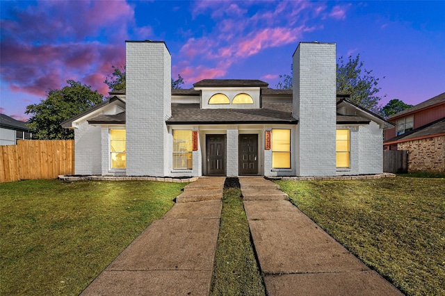 mid-century modern home with brick siding, a chimney, a front yard, and fence