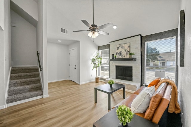 living room with a fireplace, visible vents, baseboards, stairs, and light wood-style floors