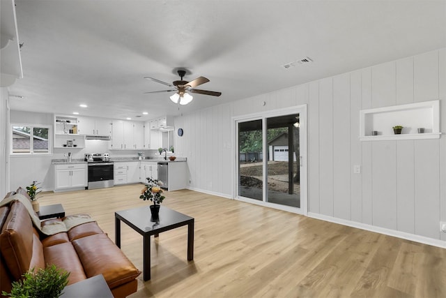 living room with ceiling fan, light wood finished floors, visible vents, and baseboards