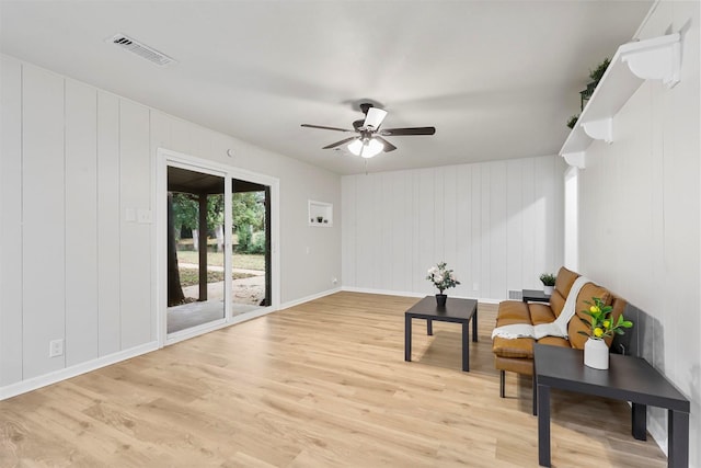 living area featuring light wood-style flooring, visible vents, ceiling fan, and baseboards