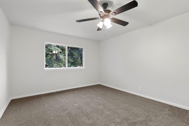 carpeted spare room featuring ceiling fan and baseboards