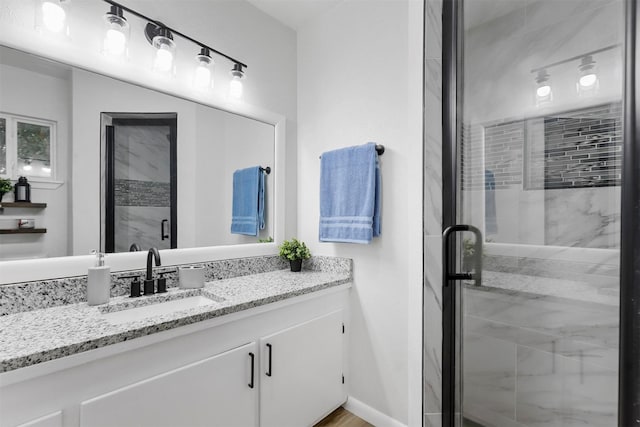 full bath featuring a stall shower, vanity, and baseboards