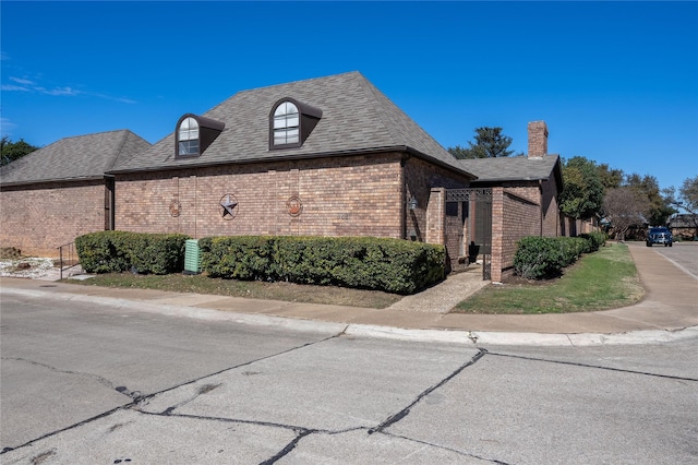 view of home's exterior featuring roof with shingles and brick siding