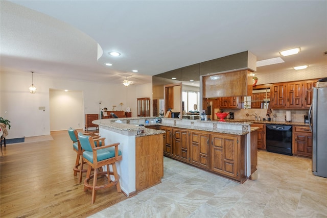 kitchen featuring dishwasher, a kitchen bar, a kitchen island, and freestanding refrigerator