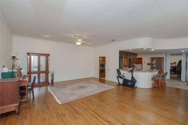 living area with a ceiling fan, visible vents, light wood-style flooring, and a textured ceiling