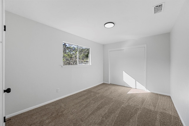 unfurnished room with carpet, visible vents, and baseboards