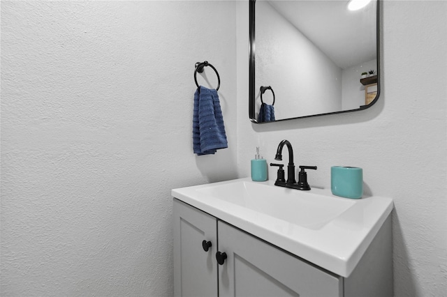 bathroom with a textured wall and vanity