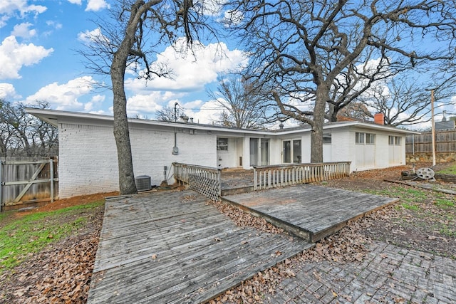 back of property with a wooden deck, a chimney, fence, and brick siding