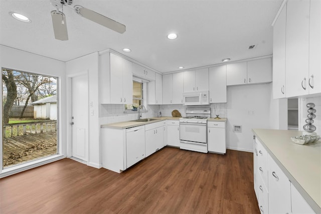 kitchen with white appliances, white cabinets, light countertops, a healthy amount of sunlight, and a sink