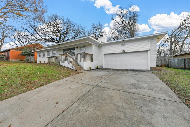 mid-century modern home featuring driveway, brick siding, a front yard, and fence