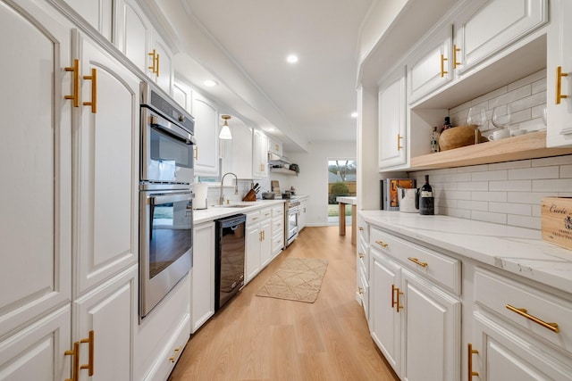 kitchen with white cabinets, light stone counters, stainless steel appliances, open shelves, and a sink