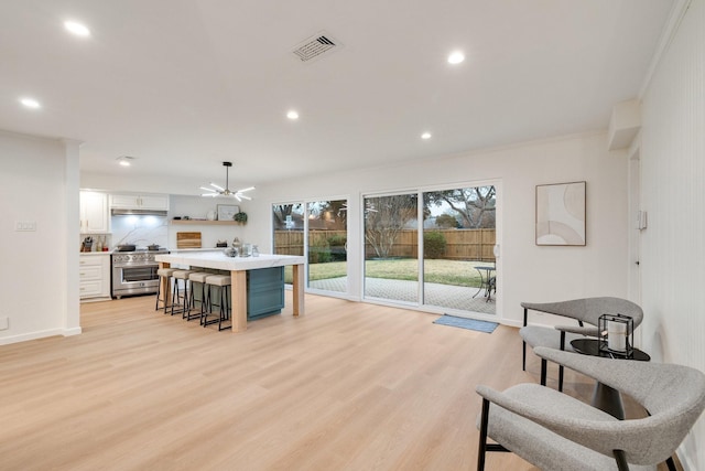 kitchen with white cabinets, a kitchen breakfast bar, decorative light fixtures, light countertops, and stainless steel stove