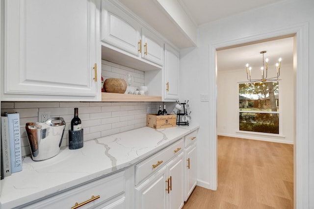 bar with pendant lighting, crown molding, light wood finished floors, backsplash, and baseboards