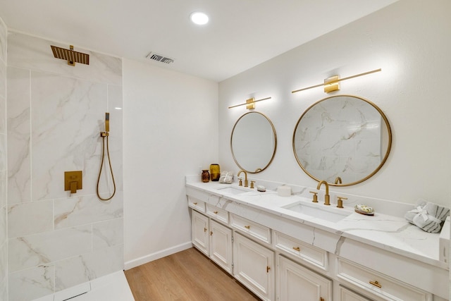 bathroom with double vanity, wood finished floors, a sink, and visible vents