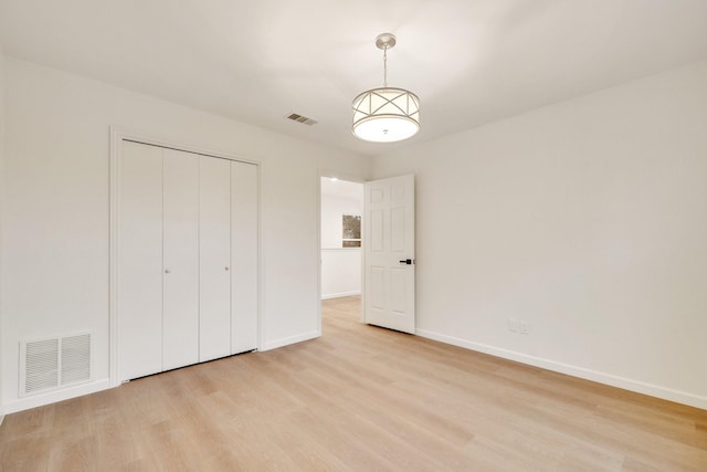 unfurnished bedroom featuring baseboards, visible vents, and light wood-style floors