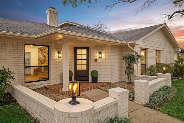 exterior space with brick siding and roof with shingles