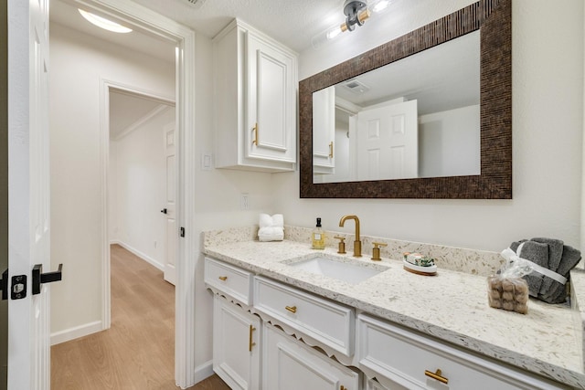 bathroom featuring visible vents, wood finished floors, vanity, and baseboards