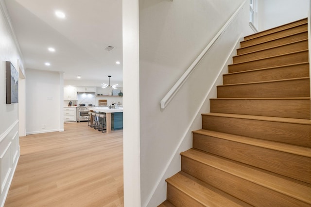 stairway featuring recessed lighting, visible vents, baseboards, and wood finished floors