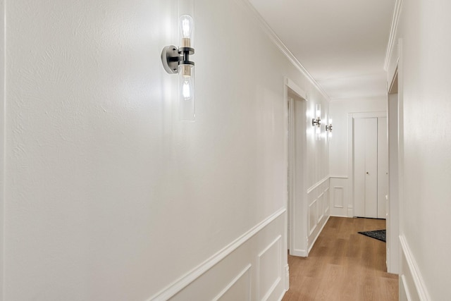 corridor with light wood finished floors and crown molding