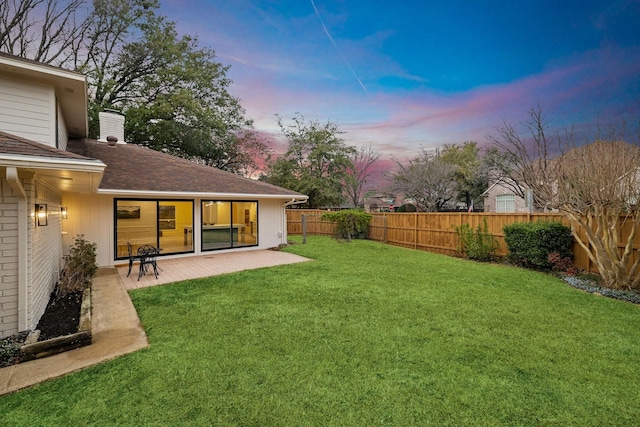 yard at dusk featuring a patio area and a fenced backyard